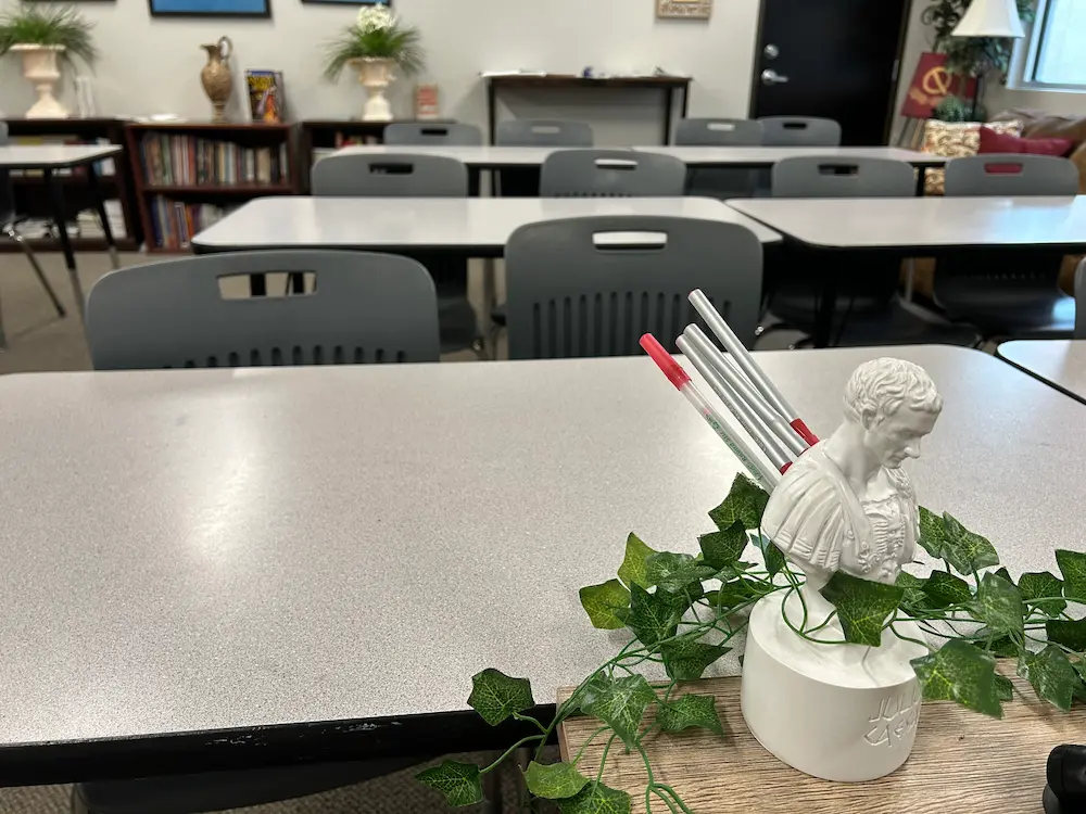 Photograph of our Latin classroom with desks in the background and a mini Julius Caesar pencil-holder statue in the foreground.
